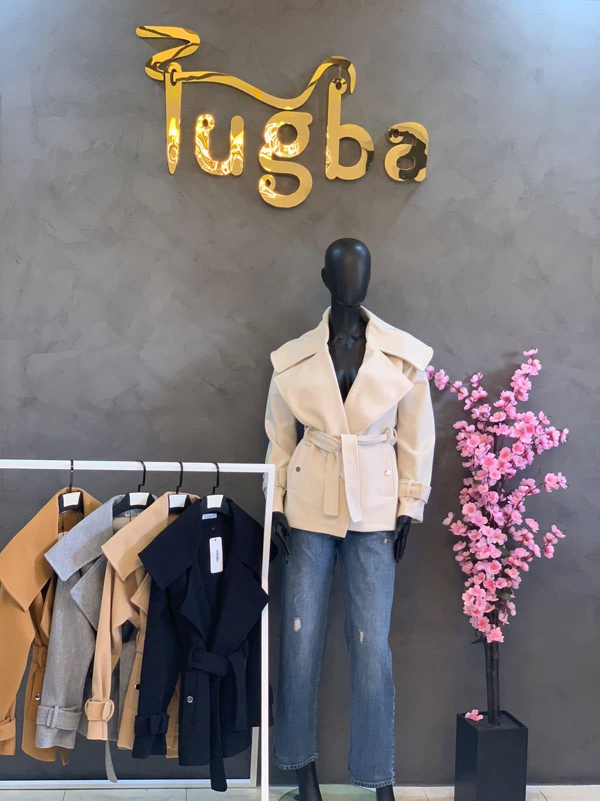 Cream belted jacket displayed beneath the Tuba store sign